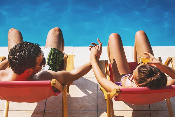 A couple sitting by the pool holding hands