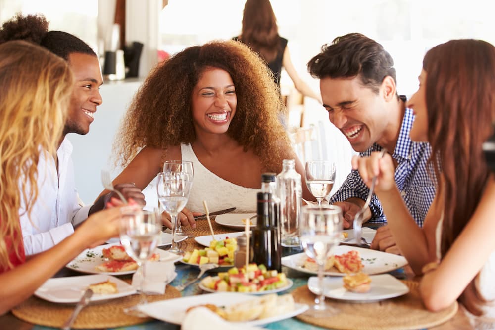 a-group-of-young-adults-laughing-enjoying-a-meal-together-at-a-table.jpg