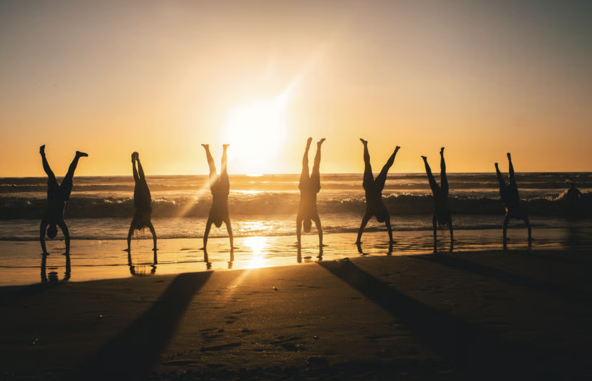 people doing handstands on the beach