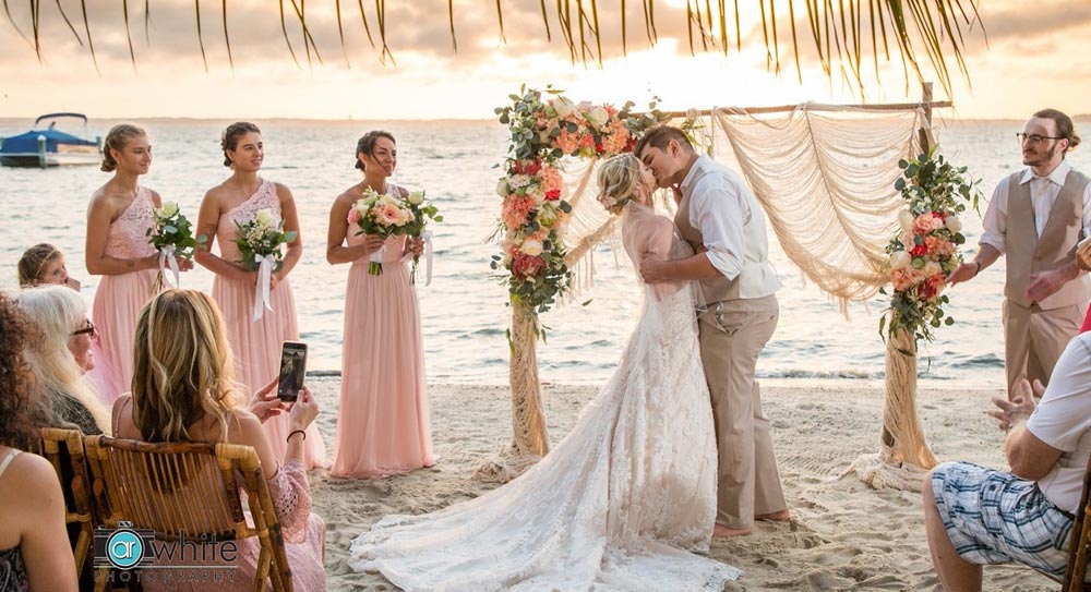 A wedding ceremony on the beach, a couple sharing a kiss
