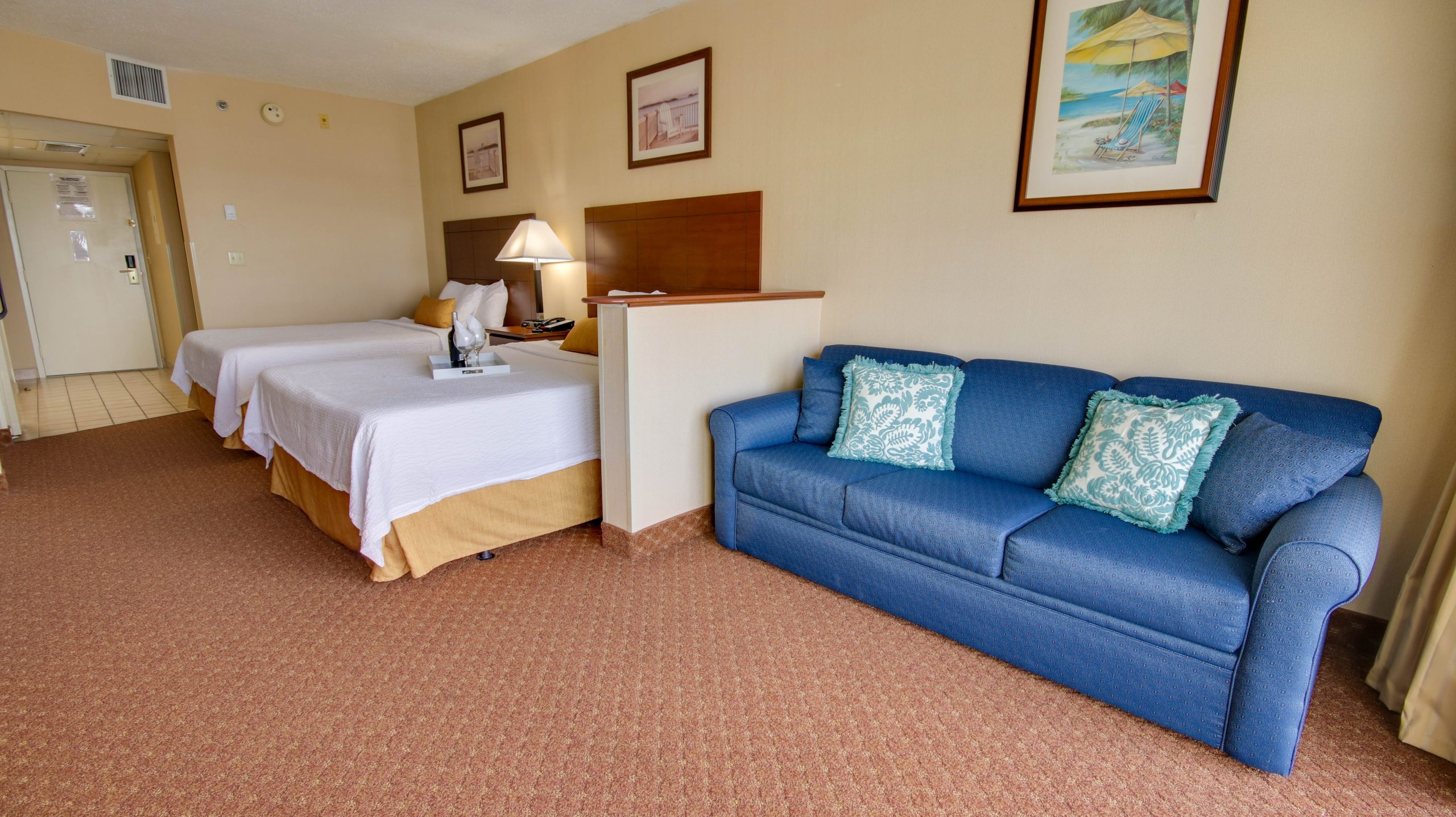 A hotel room with two double beds and a blue coach